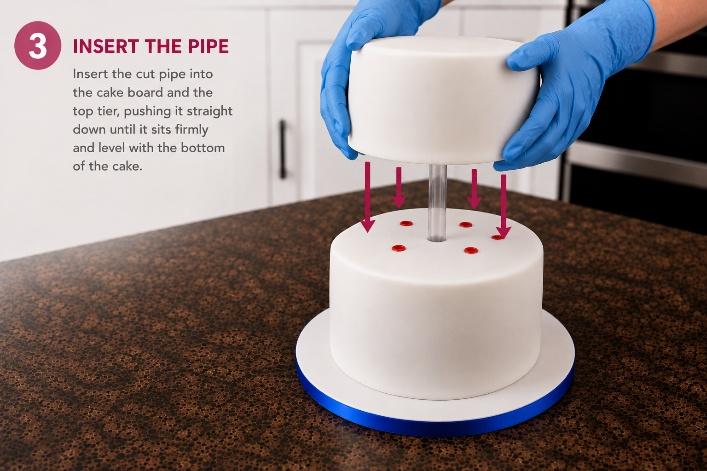 Inserting the pipe: gloved hands lower the second tier straight down over the central pipe, onto the dowelled tier below.