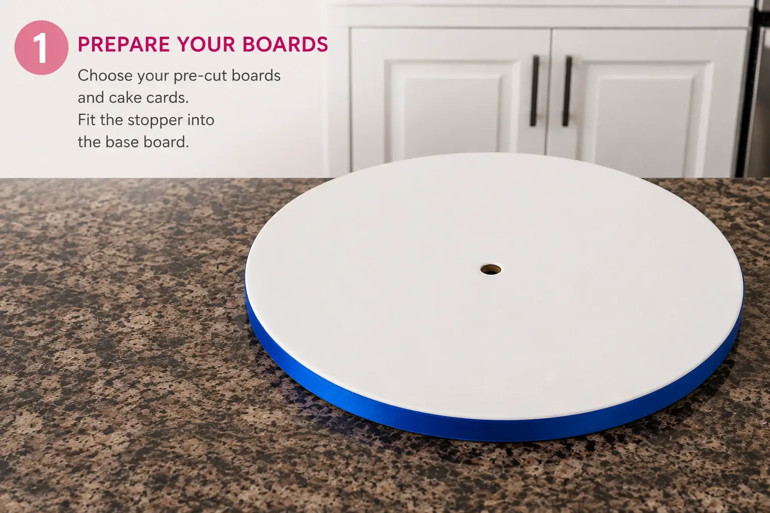 Prepare your boards: choose your pre-cut boards and cake cards, and fit the stopper into the base board. A white cake drum edged with blue ribbon sits on a kitchen worktop, its centre hole already cut.