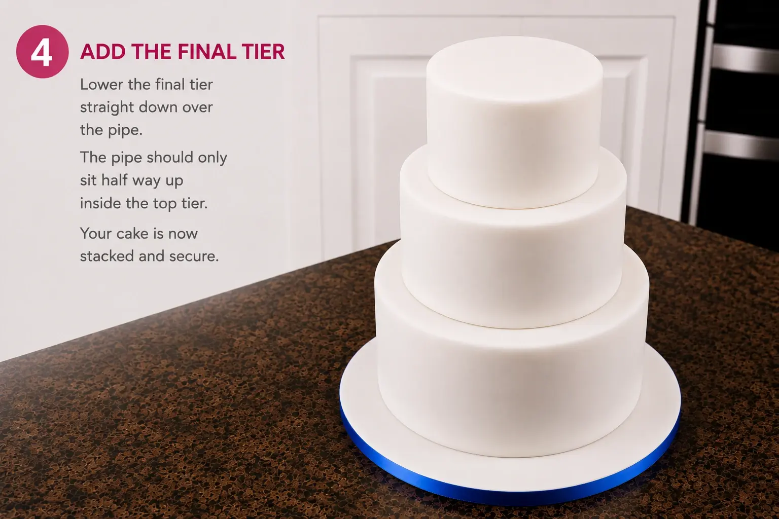 Adding the final tier: the finished three-tier cake stands on its blue-ribboned drum, the pipe hidden inside and sitting halfway up the top tier.
